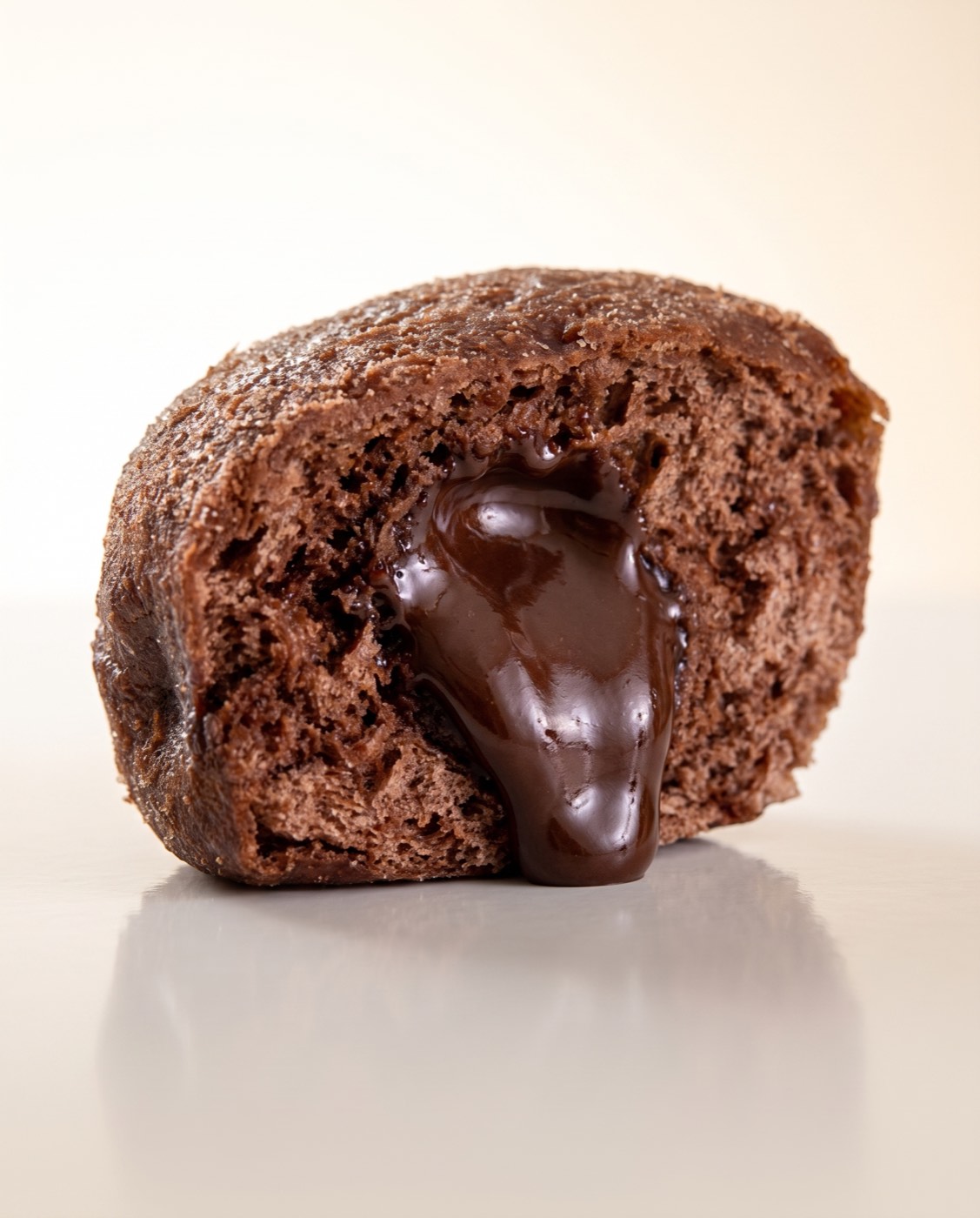 Chocolate Berliner split in half with chocolate filling oozing, on a clean background